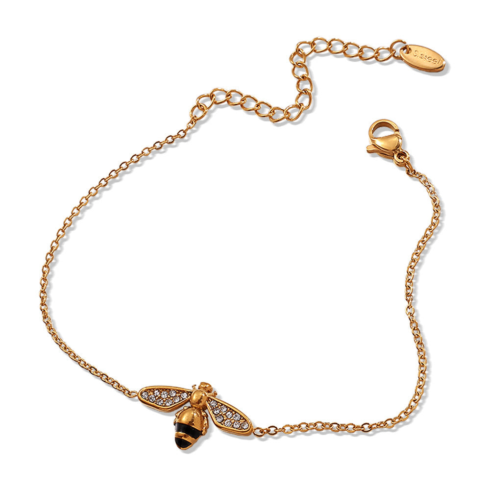 Gold bracelet with a bee charm on a white background