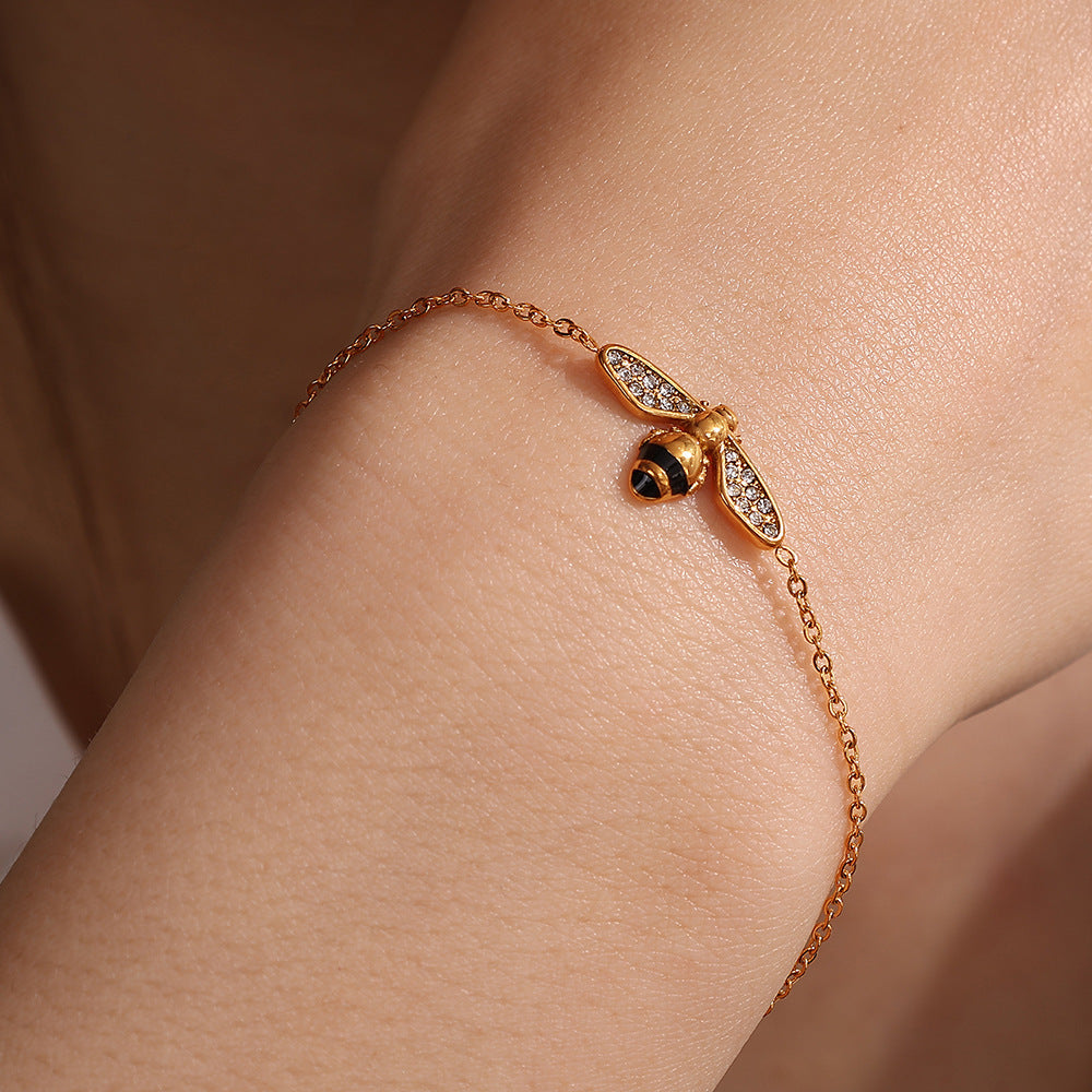 Gold bracelet with a ladybug charm on a wrist against a neutral background