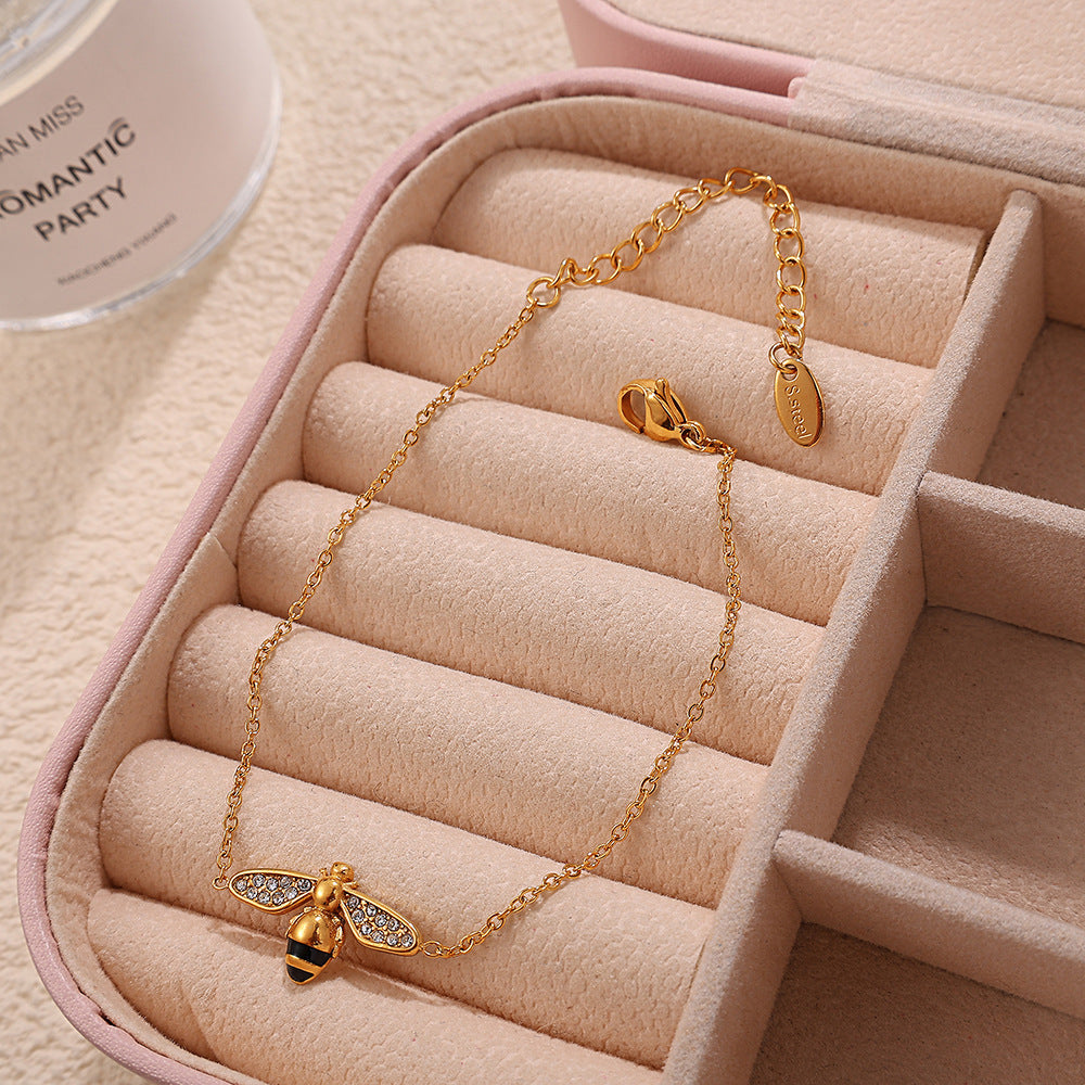 Gold bee necklace in a jewelry box with a soft pink interior